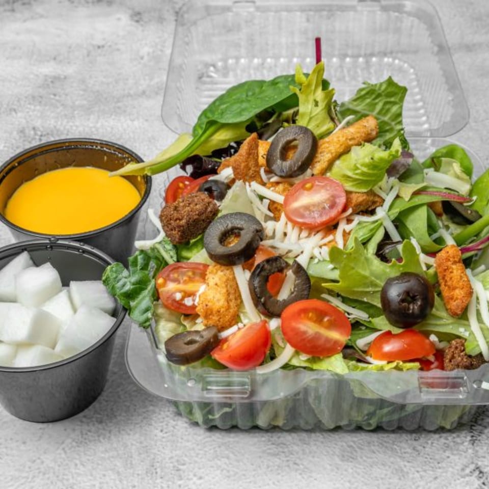 DAK Korean Fried Chicken's side salad with dressing and pickled radish cubes in takeout containers.